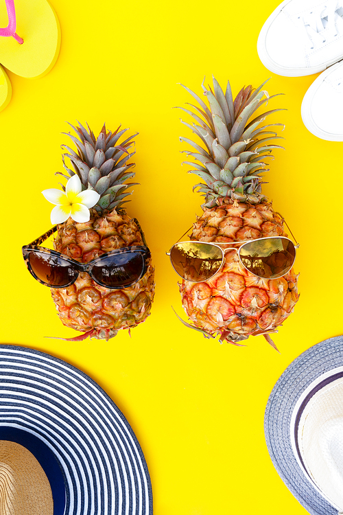 Summer top view flat lay pattern with pair pineapples in sunglasses on yellow background