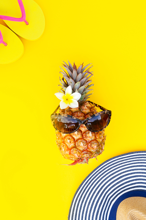Summer flat lay top view with funny pineapple on yellow background