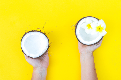 someone hands holding coconut cut open fruit on yellow background