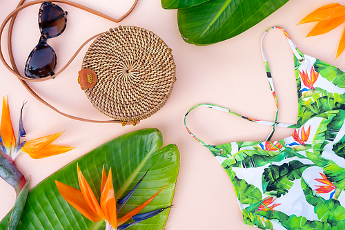 Summer flat lay scenery with tropical leaves on pink background close up