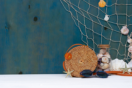 Summer sea still life with straw bag, seashells and fishing net with copy space
