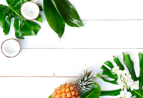 Summer flat lay scenery with tropical leaves and friuts on white background with copy space