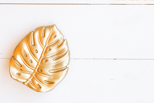 Monstera golden leaf, styled top view natural background on white wooden planks with copy space