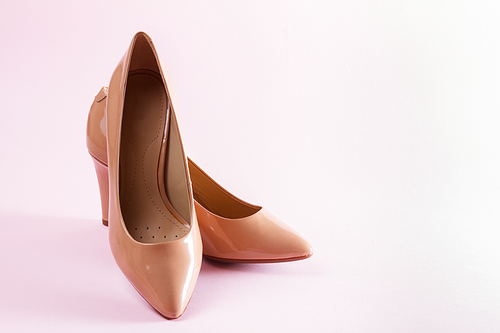 Pair of elegant leather high heel shoes on pink background