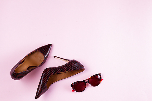 Pair of Elegant high heel shoes and sunglasses on pink background