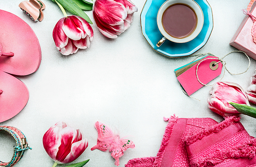 Springtime womens workspace with tulips flowers, pink clothes and shoes, tags and coffee cup, top view, frame