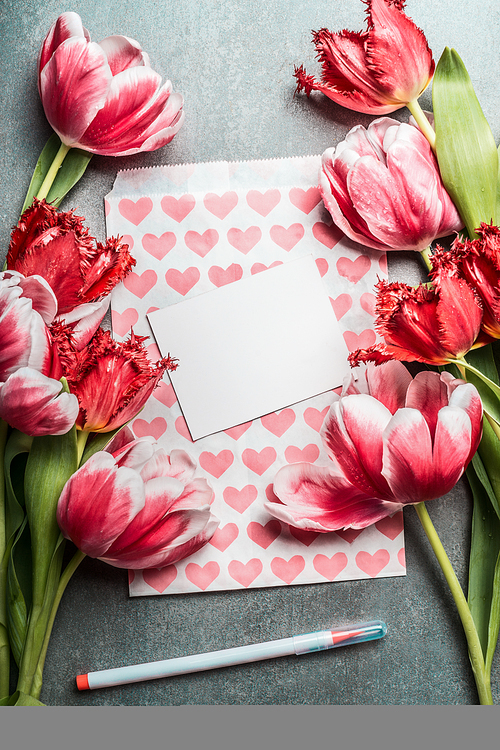 Springtime greeting card mock up with pretty tulips, hearts, white blank card and pen, top view, frame. Layout  or greeting for Mothers day, wedding or happy event