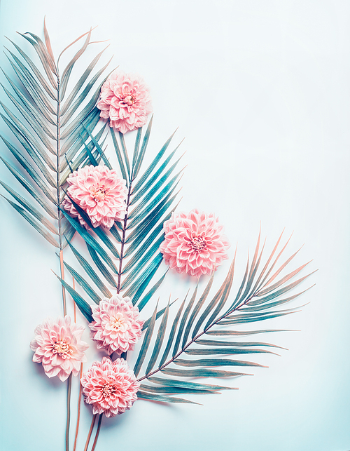 Creative layout with tropical palm leaves and pastel pink flowers on  turquoise blue desktop background, top view, place for text, vertical