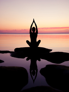 caucasian fitness woman practicing yoga on the beach at sunset