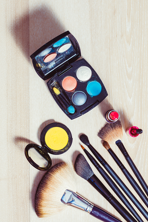 Set for make-up: brushes and cosmetic products on wooden table, close-up