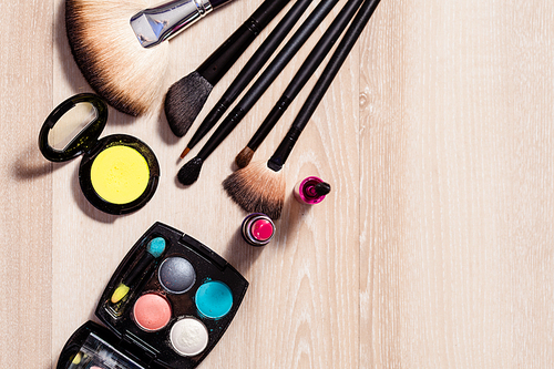 Set for make-up: brushes and cosmetic products on wooden table, close-up