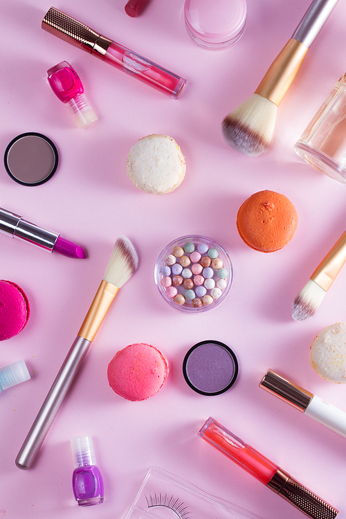 Make up products and macaroons pattern on pink background