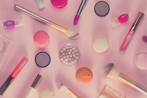 Make up products and macaroons pattern on pink background, retro toned