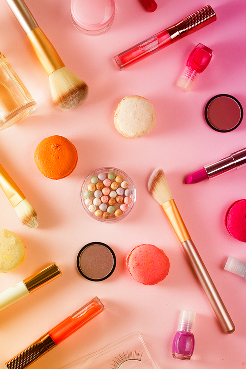 Make up products and macaroons pattern on pink background, toned