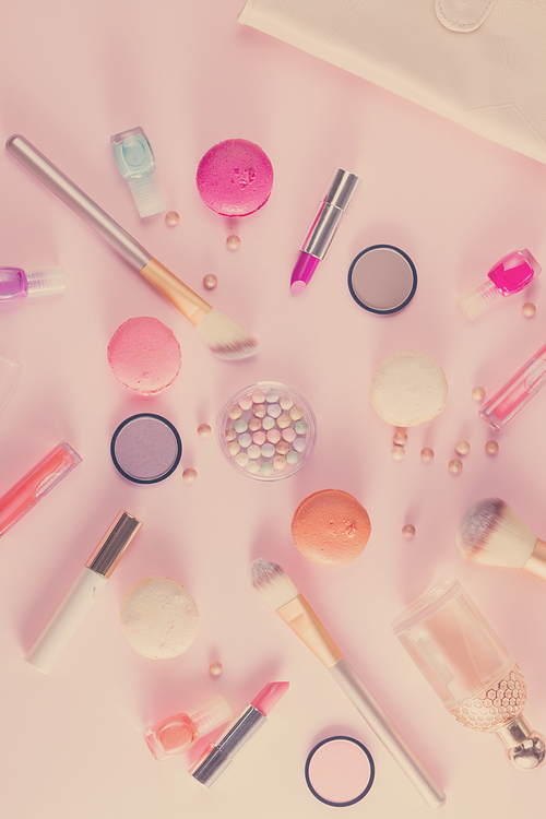 Make up products and macaroons on pink background, retro toned