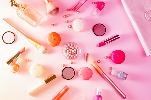 Make up products and macaroons on pink background, toned