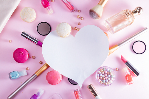 Make up products and macaroons flat lay layot with copy space on pink background