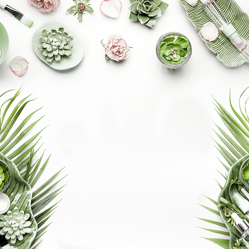 Modern natural skin care equipment with roses, succulents, facial mist water spray and green tropical leaves on white background, top view, flat lay, frame. Beauty concept