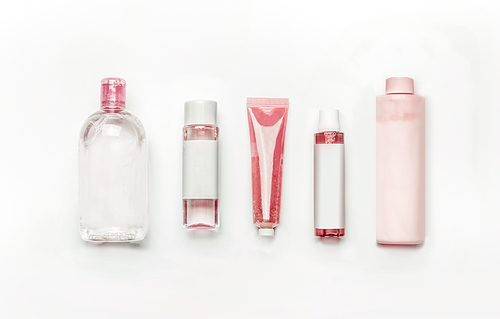 Pink natural cosmetic products : gel, lotion, serum, micellar water and toner,   bottles and tubes with branding mock up on white desk background , top view, flat lay . Facial skin care and beauty