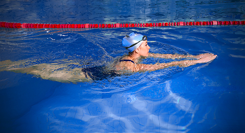 Young woman swimmer in blue pool water