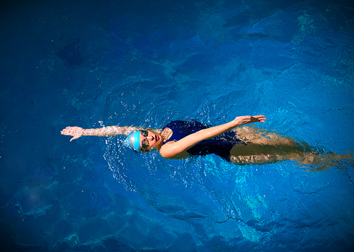 Young woman swimmer in blue pool water