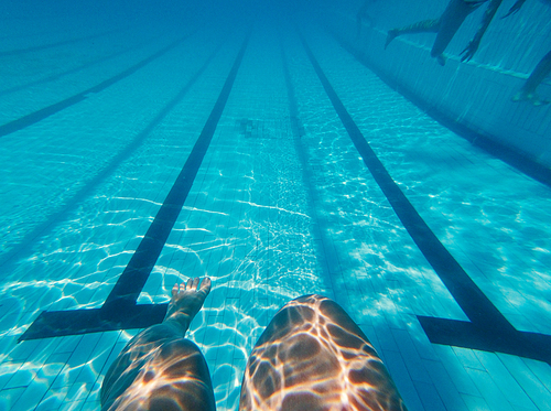 Womans legs underwater in swimming pool