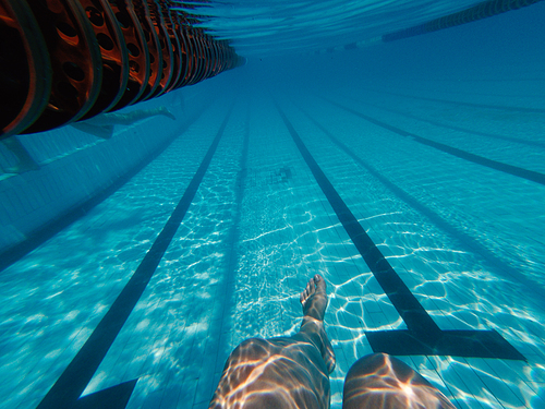 Womans legs underwater in swimming pool near pools bottom