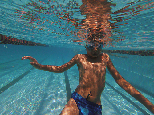 Boy swimming underwater in swimming pool in goggles