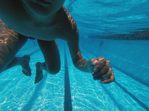 Boys body swimming underwater near pools bottom