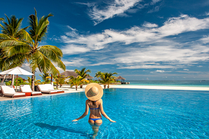 Woman with sun hat at beach pool in Maldives