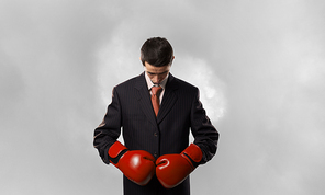 Young businessman in red boxing gloves on white background