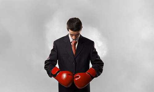 Young businessman in red boxing gloves on white background