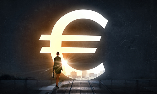 Silhouette of businesswoman in light of big euro symbol