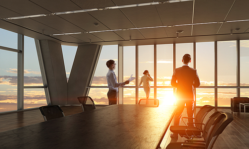 Group of business people working in office in lights of sunset