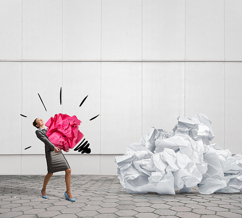 Woman carrying with effort big crumpled ball of paper as creativity sign