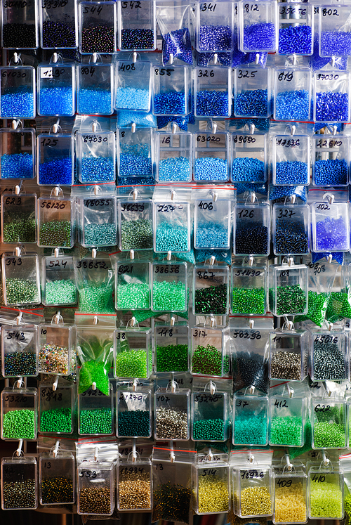 Colorfull glass beads batches in plastic bags for beadwork in craft shop