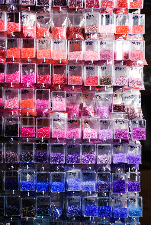 Colorfull glass beads batches in plastic bags for beadwork in craft shop