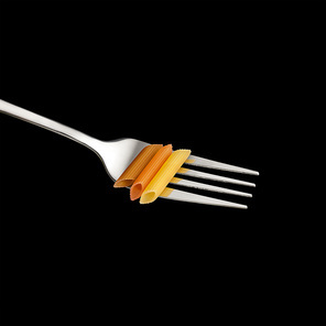 Creative still life photo of a fork with raw pasta on black background.