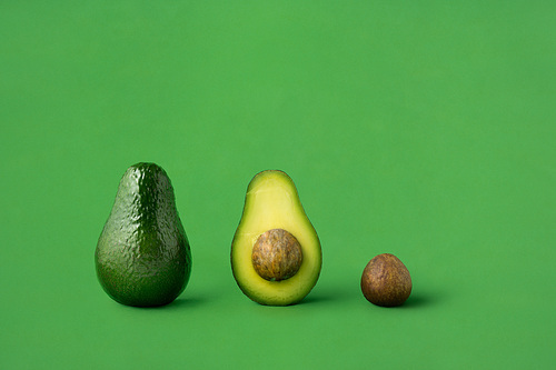 Creative concept photo of avocados on green background.