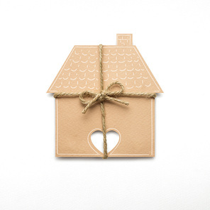 Creative concept photo of a house with a bow made of paper on white background.