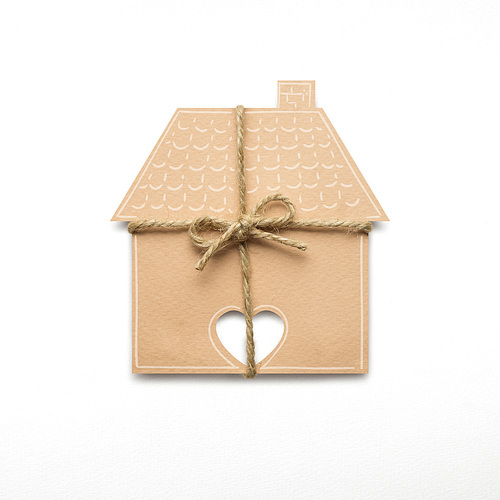 Creative concept photo of a house with a bow made of paper on white background.