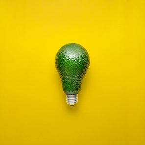 Creative concept photo of avocado as electric bulb on yellow background.