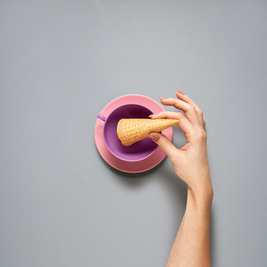Creative concept photo of kitchenware with hand, painted plate with food on it on grey background.