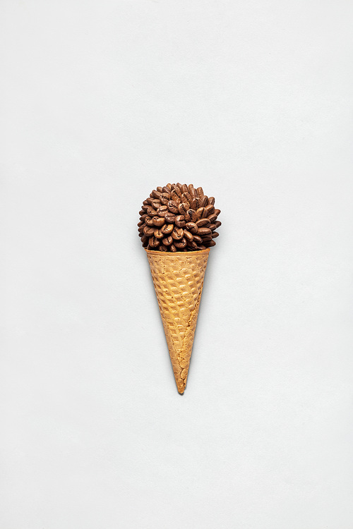 Creative concept photo of waffle cone filled with coffee on grey background.