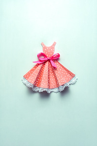 Creative concept photo of a dress with a bow made of paper on mint background.