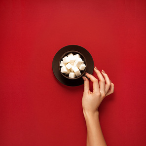 Creative concept photo of kitchenware with hand, painted plate with food on it on red background.