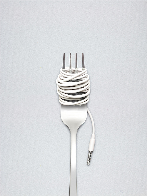 A shining fork with noodle made of cable with music jack plug in metal background.