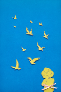 Creative concept photo of girl with seagulls made of paper on blue background.