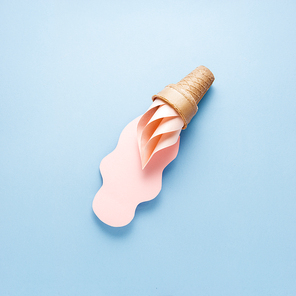 Creative concept photo of ice cream cone and splash made of paper on blue background.