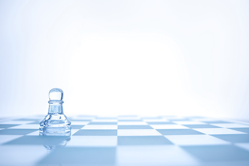A conceptual photo of loenely glass pawn on the chessboard.